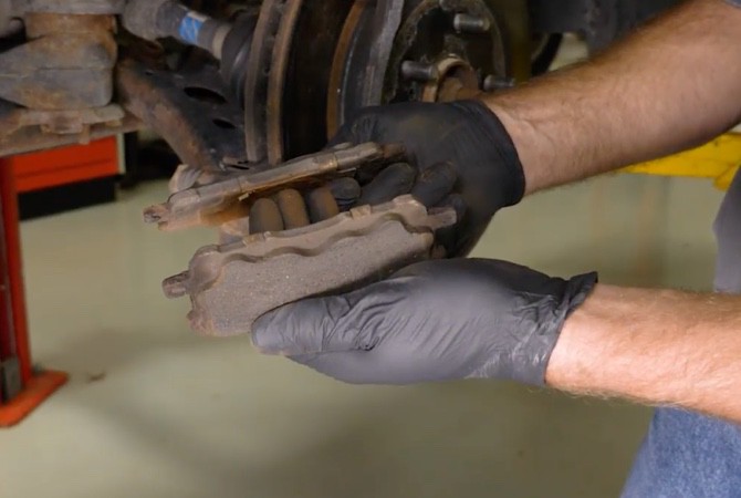 Technician examining brake pads in a brake system